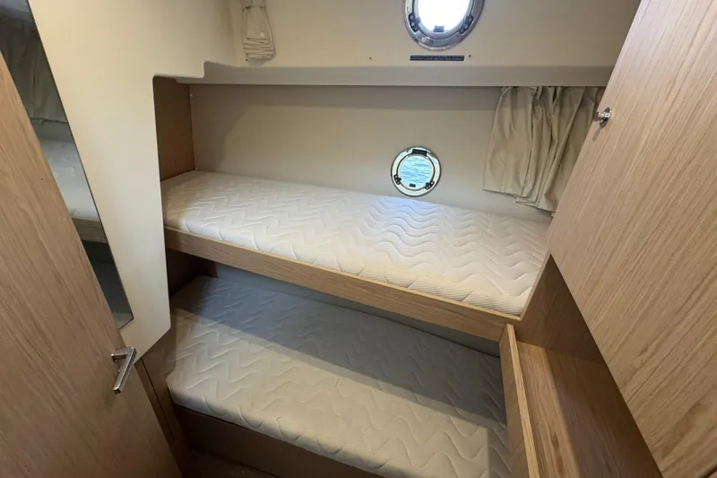 Slide: The Image of 2023 Beneteau Swift Trawler 35 cabin with bunk beds and porthole window. - 43