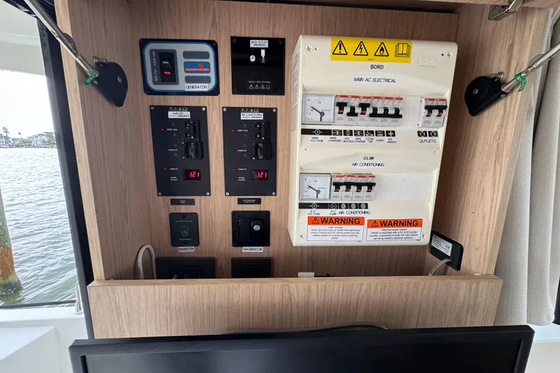 Slide: The Image of Electrical control panel on 2023 Beneteau Swift Trawler 35, featuring switches and warning labels. - 44