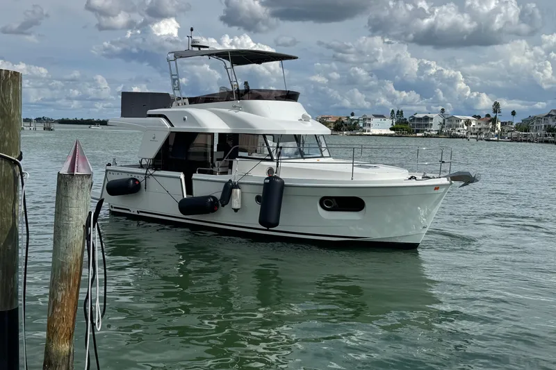 Slide: The Image of 2023 Beneteau Swift Trawler 35 cruising on a calm waterway under a cloudy sky. - 46