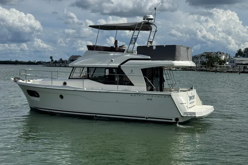 Slide: The Image of 2023 Beneteau Swift Trawler 35 cruising on calm waters under a cloudy sky. - 5