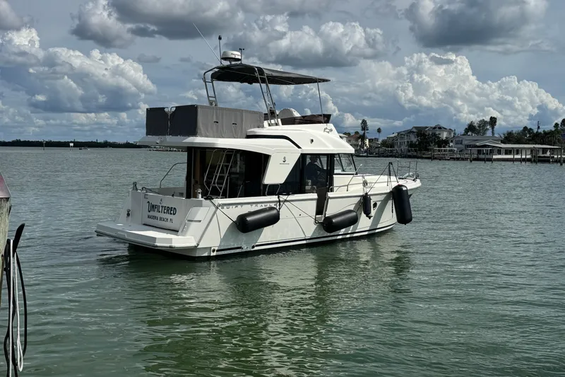 Slide: The Image of 2023 Beneteau Swift Trawler 35 on calm water under cloudy sky. - 9