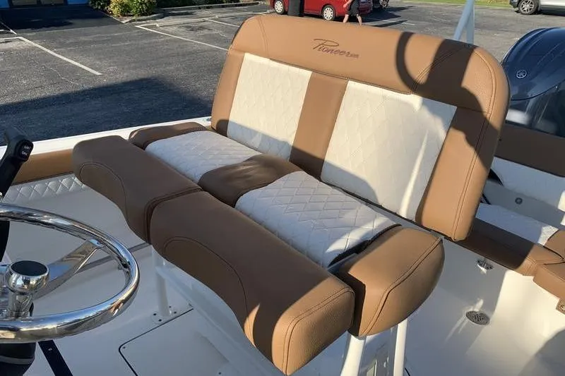 Slide: The Image of 2026 Pioneer ISLANDER 202 boat seat with tan and white upholstery in a parking lot. - 12