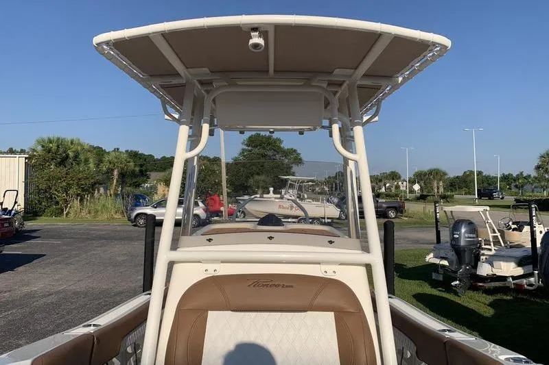 Slide: The Image of 2026 Pioneer ISLANDER 202 boat with T-top and seating, parked outdoors. - 27