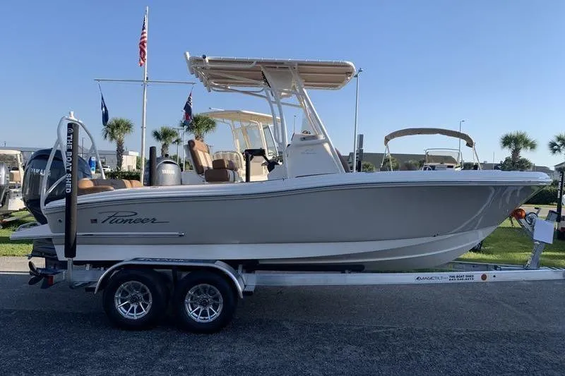 Slide: The Image of 2026 Pioneer ISLANDER 202 boat on trailer, displayed outdoors with flags and palm trees. - 5