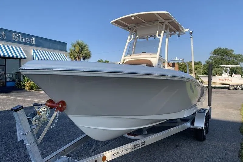 Slide: The Image of 2026 Pioneer ISLANDER 202 boat on trailer, parked outside a shop under clear blue sky. - 8