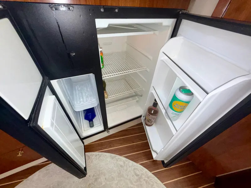 Slide: The Image of Open refrigerator inside 2009 Cruisers Yachts 420 Coupe, showing beverages and wooden flooring. - 32