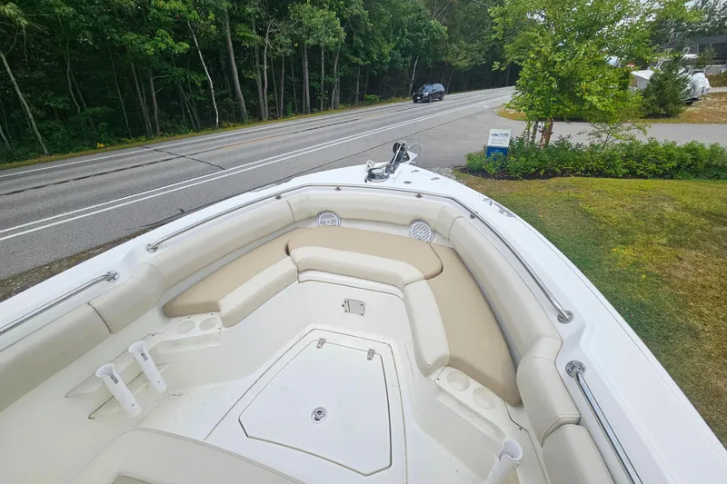 Slide: The Image of 2019 Boston Whaler 230 Outrage boat with beige seating, parked near a road and greenery. - 14