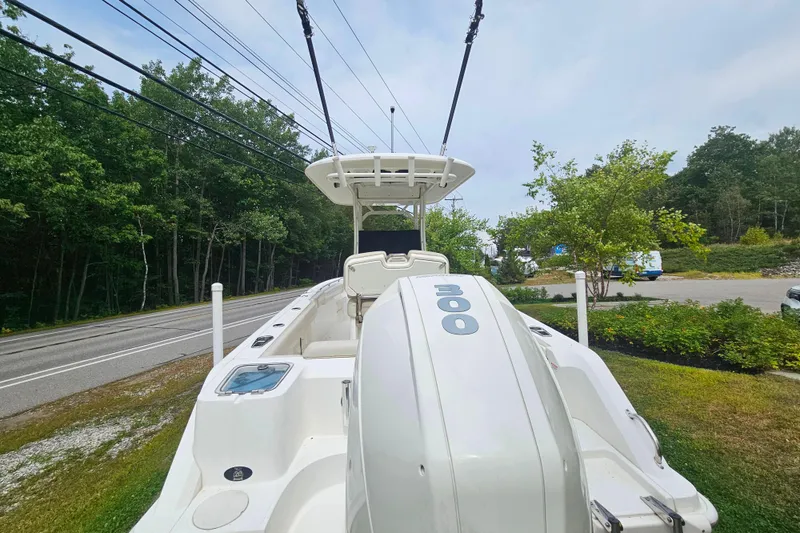Slide: The Image of 2019 Boston Whaler 230 Outrage boat with powerful outboard motor, parked near a road. - 2
