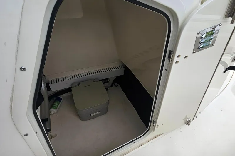 Slide: The Image of 2019 Boston Whaler 230 Outrage boat interior with storage compartment and portable toilet. - 21