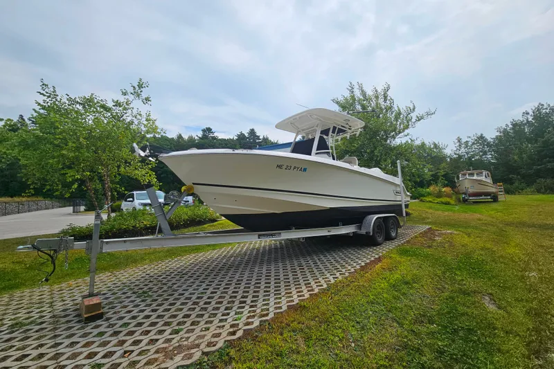 Slide: The Image of 2019 Boston Whaler 230 Outrage boat on trailer, parked on grassy area. - 22