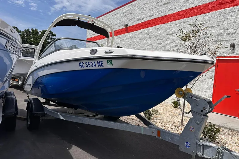 Slide: The Image of 2024 Yamaha Boats AR195 on trailer, blue and white hull, parked outdoors. - 1