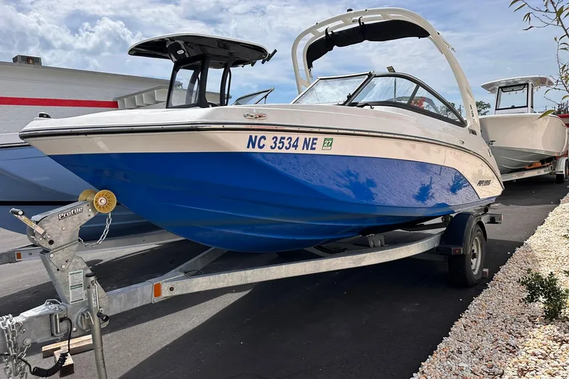 Slide: The Image of 2024 Yamaha Boats AR195 on trailer, blue and white design, parked outdoors. - 2