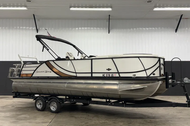 The Image of 2022 South Bay 523 UL pontoon boat on trailer in indoor storage. - 0
