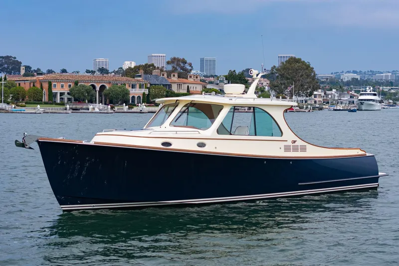 Slide: The Image of 2014 Hinckley Talaria 34 yacht on calm water with scenic waterfront backdrop. - 0