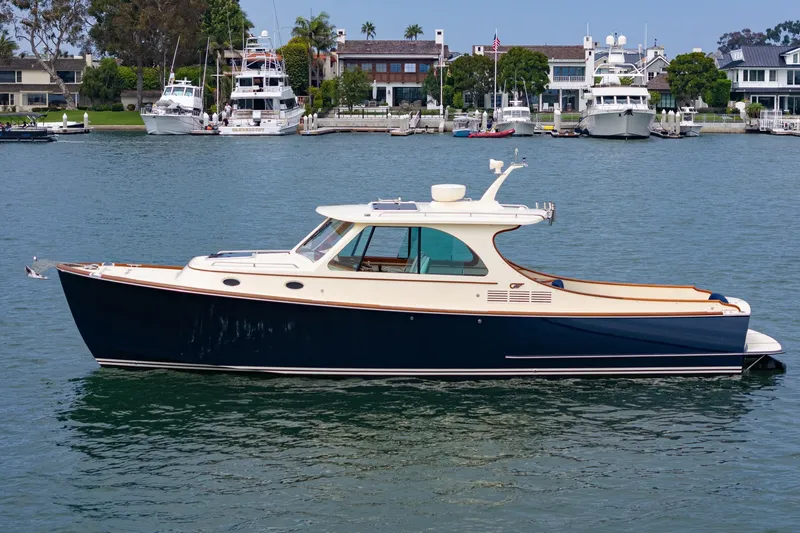 Slide: The Image of 2014 Hinckley Talaria 34 yacht on calm water, with waterfront homes in the background. - 1