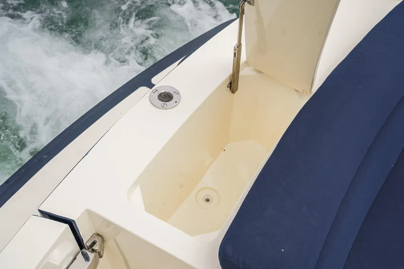 Slide: The Image of 2014 Hinckley Talaria 34 boat storage compartment with blue seating and water backdrop. - 12