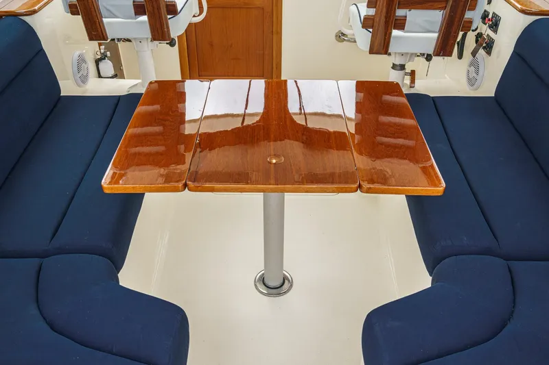 Slide: The Image of Interior of 2014 Hinckley Talaria 34 with polished wood table and blue seating. - 14