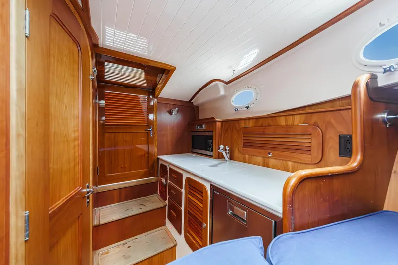 Slide: The Image of 2014 Hinckley Talaria 34 interior with wooden cabinetry, sink, and microwave. - 26