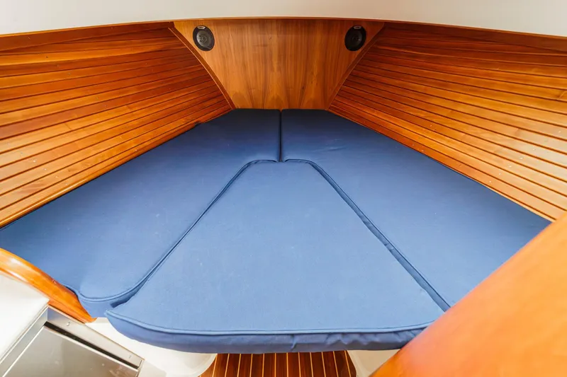 Slide: The Image of 2014 Hinckley Talaria 34 interior with blue cushioned berth and wooden paneling. - 32
