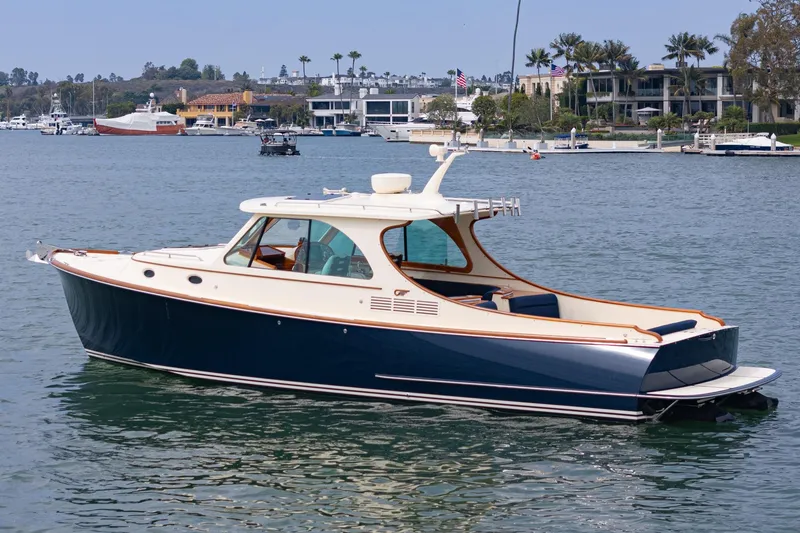 Slide: The Image of 2014 Hinckley Talaria 34 yacht on calm waters near luxury waterfront homes. - 43