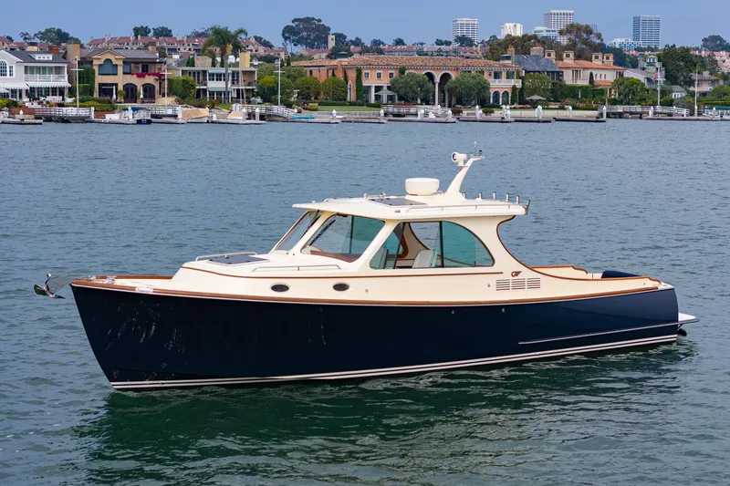 Slide: The Image of 2014 Hinckley Talaria 34 yacht on calm water near luxury waterfront homes. - 44