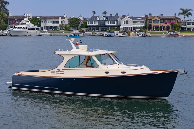 Slide: The Image of 2014 Hinckley Talaria 34 yacht on calm water near luxury waterfront homes. - 45