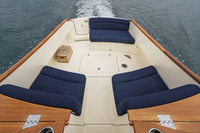 Slide: The Image of 2014 Hinckley Talaria 34 boat deck with blue cushioned seating and wooden accents. - 9