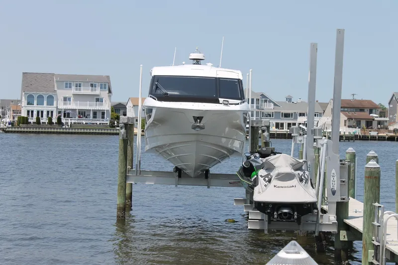 Slide: The Image of 2022 Galeon 325 GTO yacht docked with Kawasaki jet ski, waterfront homes in background. - 0