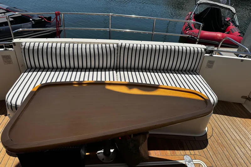Slide: The Image of Striped seating and wooden table on 2001 Fairline 55 yacht deck by the water. - 8