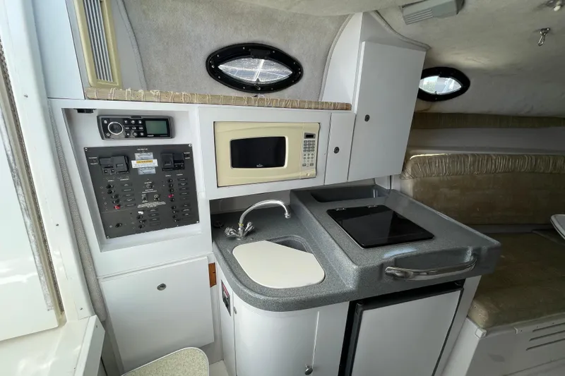 Slide: The Image of 2002 Wellcraft 290 Coastal cabin interior with beige seating and compact table. - 19