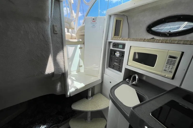 Slide: The Image of 2002 Wellcraft 290 Coastal boat interior with kitchenette, microwave, and control panel. - 23