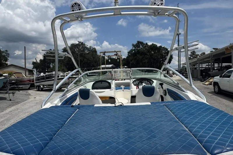 Slide: The Image of 2011 Sea Ray 205 Sport boat with blue seating, parked outdoors under a cloudy sky. - 2