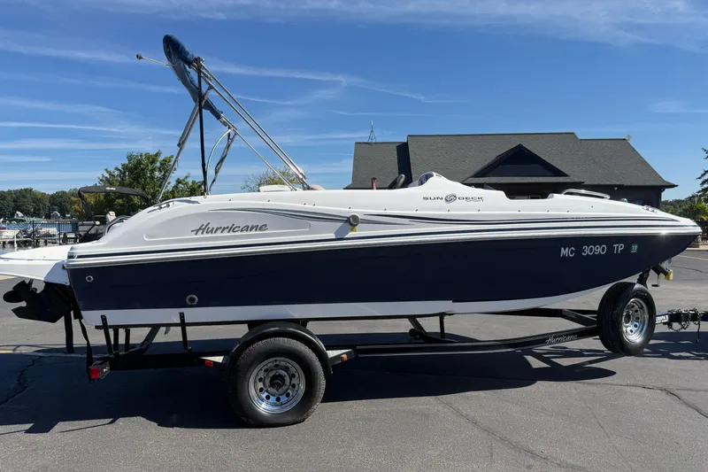 Slide: The Image of 2013 Hurricane 188 boat on trailer, parked outdoors under clear blue sky. - 19