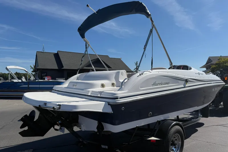 Slide: The Image of 2013 Hurricane 188 boat with canopy on trailer, parked outdoors under clear sky. - 24