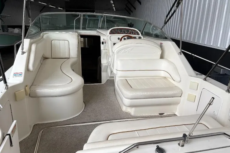 Slide: The Image of 1999 Sea Ray 270 Sundancer boat interior with white seating and helm. - 5