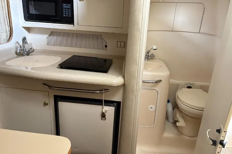 Slide: The Image of 1999 Sea Ray 270 Sundancer interior with kitchenette and compact bathroom. - 7