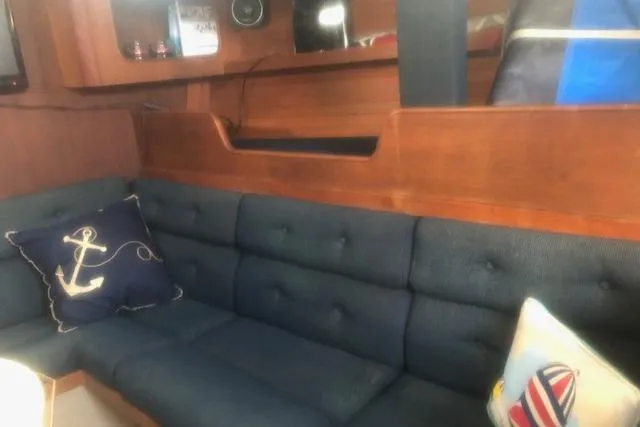 Slide: The Image of Interior of 1988 C&C 44 yacht with blue cushioned seating and nautical-themed pillows. - 14