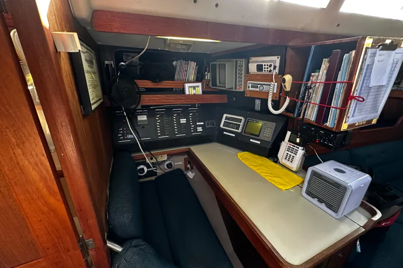 Slide: The Image of Navigation station inside a 1988 C&C 44 sailboat, featuring communication equipment and storage. - 25