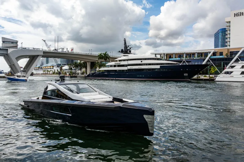 Slide: The Image of Modern Maori 54 yacht cruising near a bridge, with luxury yachts docked nearby, 2023. - 16