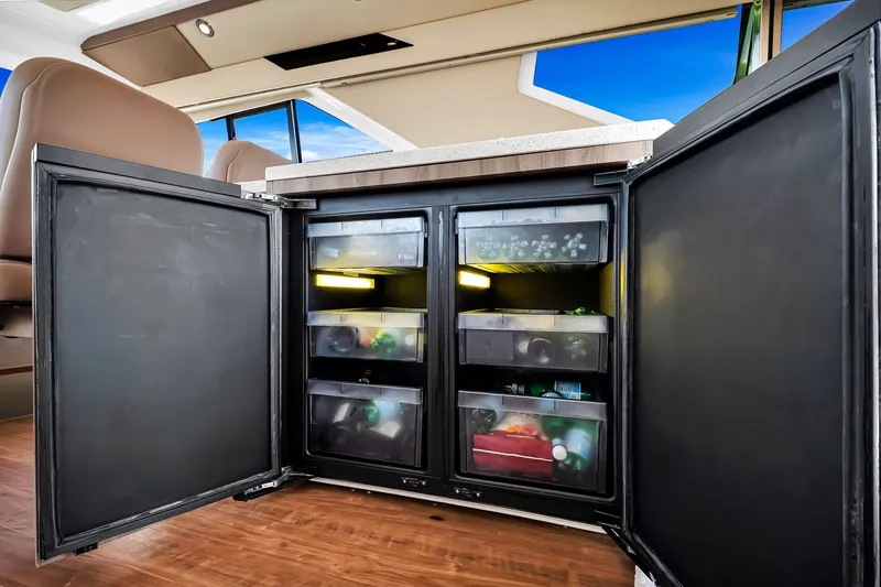 Slide: The Image of Open refrigerator inside 2017 Regal 53 Sport Coupe yacht, showcasing organized storage compartments. - 43