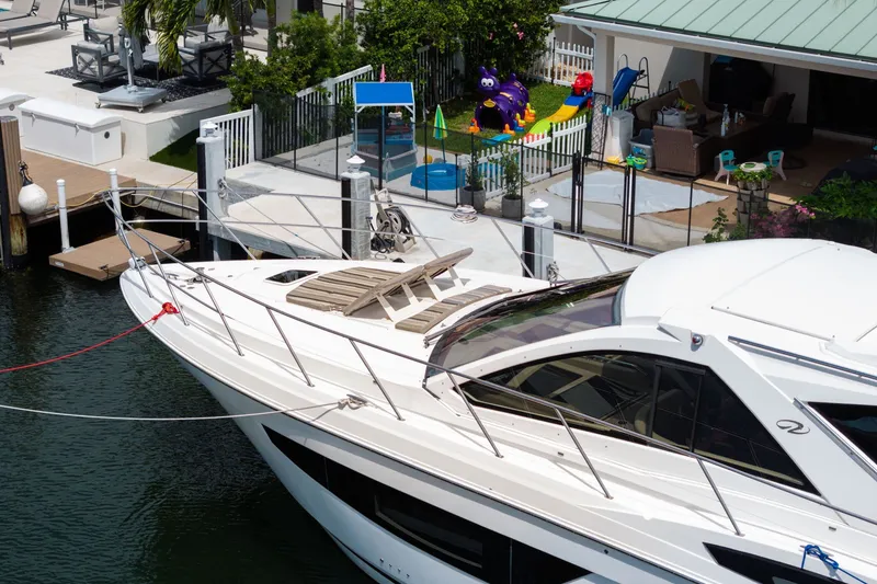 Slide: The Image of 2017 Regal 53 Sport Coupe yacht docked near a waterfront home with a playground. - 13