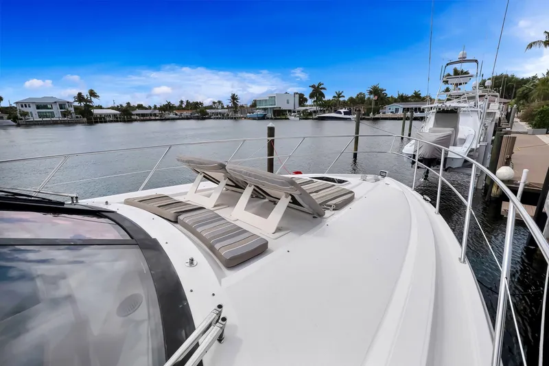 Slide: The Image of 2017 Regal 53 Sport Coupe yacht docked, featuring sun loungers and scenic waterfront view. - 9