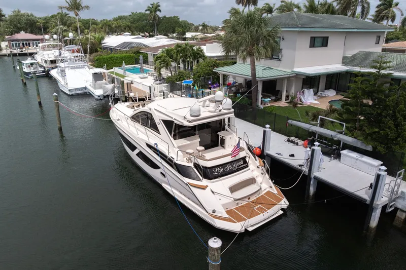 Slide: The Image of 2017 Regal 53 Sport Coupe yacht docked by waterfront home, surrounded by palm trees. - 24