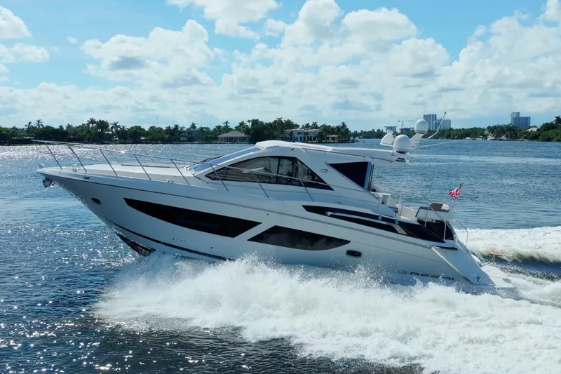 Slide: The Image of 2017 Regal 53 Sport Coupe yacht cruising on a sunny day, creating waves. - 2