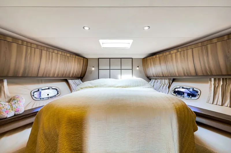 Slide: The Image of Luxurious bedroom interior of 2017 Regal 53 Sport Coupe yacht with wood cabinetry and porthole windows. - 63