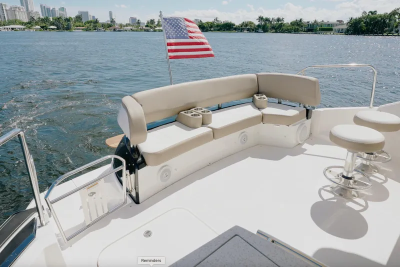 Slide: The Image of 2017 Regal 53 Sport Coupe yacht deck with seating and American flag on water. - 7