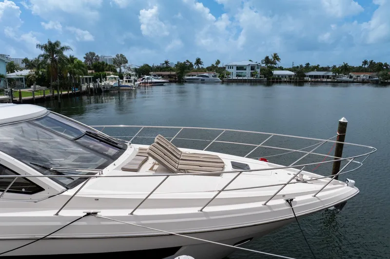 Slide: The Image of 2017 Regal 53 Sport Coupe yacht docked by waterfront homes under a cloudy sky. - 15