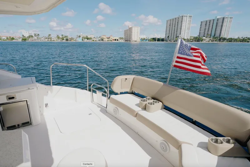 Slide: The Image of 2017 Regal 53 Sport Coupe yacht deck with American flag, overlooking coastal skyline. - 8