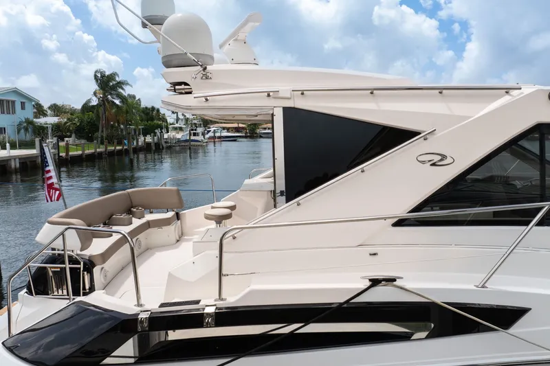 Slide: The Image of 2017 Regal 53 Sport Coupe yacht docked by a scenic waterfront. - 27