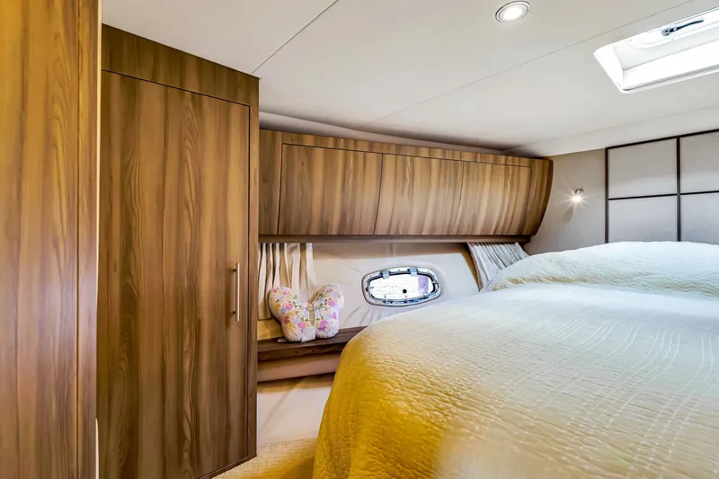 Slide: The Image of Luxurious cabin interior of 2017 Regal 53 Sport Coupe with wood finish and cozy bedding. - 64